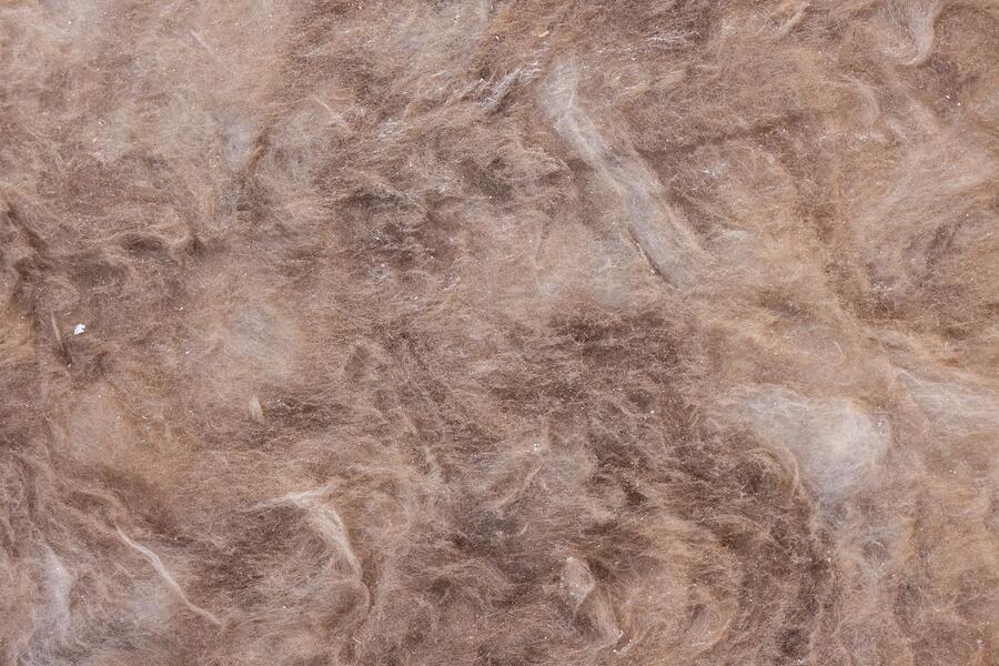 The surface of loose-fill attic insulation, flattened in places