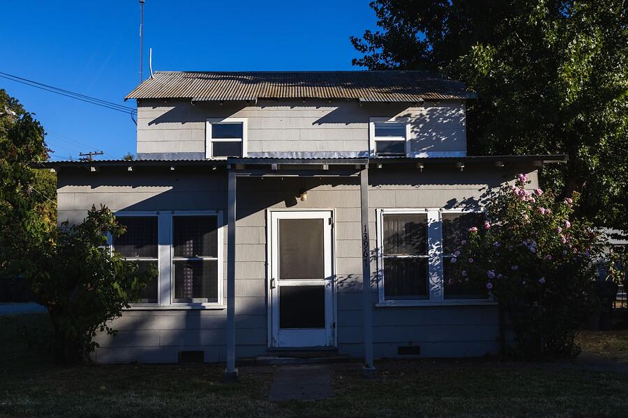 A two-story Davis house half hidden by mature trees