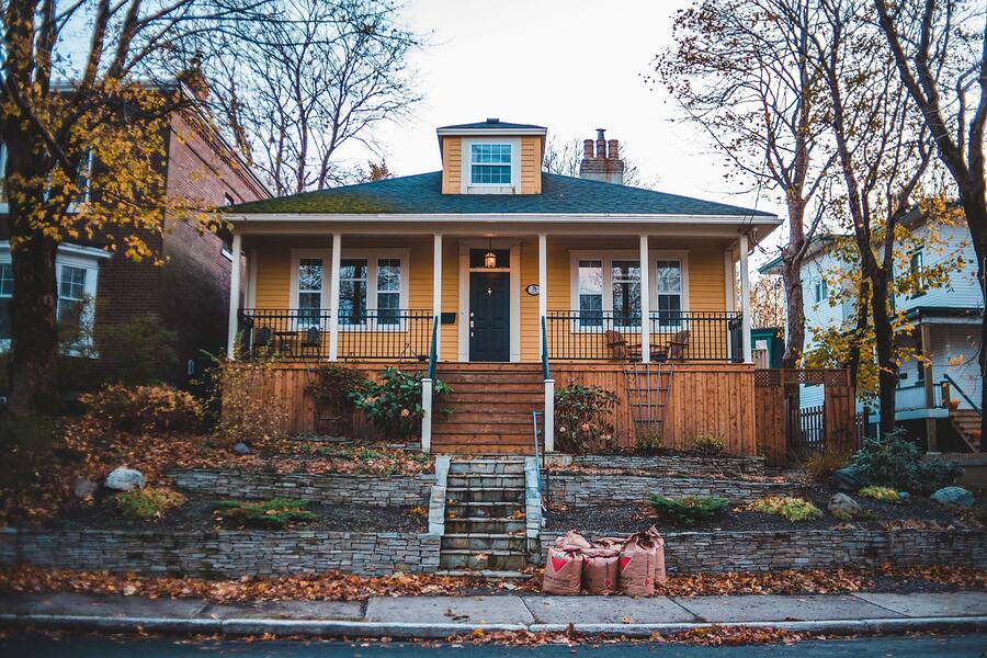 A yellow Craftsman bungalow with a deep porch and original wood siding